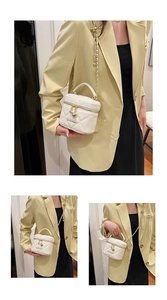 Détail du sac à main matelassé blanc avec chaîne dorée et pendentif cœur de zip