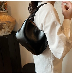 Seitenansicht einer glänzend schwarzen minimalistischen Ledertasche als Umhängetasche