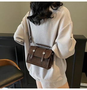 Détail du sac bandoulière vintage marron foncé avec texture brillante et boucles