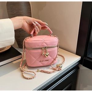Détail du sac à main matelassé rose avec breloques cœur dorées et logo métallique