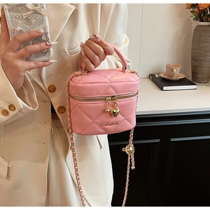 Détail du sac cylindrique matelassé rose avec chaîne dorée et fermeture éclair cœur