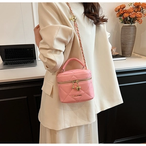 Détail d'un sac bandoulière rose matelassé avec pendentifs cœur et logo en métal