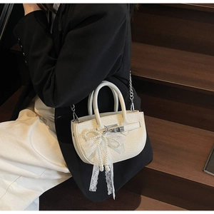 Detail of creamy white litchi leather mini bag with silver chain and lace pearl bow