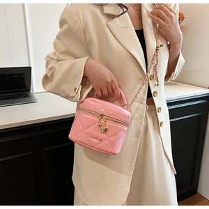 Vue détaillée du sac matelassé rose avec bandoulière dorée et breloque zip en cœur