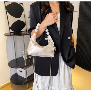 Detail of plum blossom embroidery and translucent beaded handle on white satin handbag
