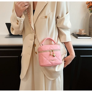 Détail du sac matelassé rose avec un pendentif en forme de cœur doré sur la fermeture