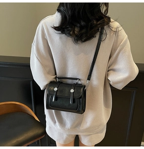 Détail d'un petit sac carré noir avec rivets argentés porté par un mannequin avec style