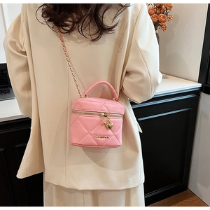 Vue détaillée du sac cylindrique rose matelassé avec un pendentif en forme de cœur doré