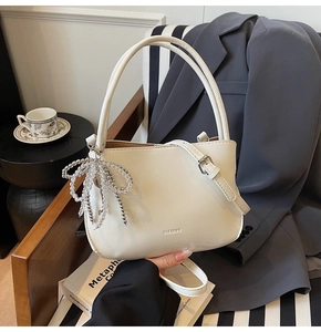 Detailansicht der weißen Leder-Beuteltasche mit CLEARDK-Logo und Perlen-Schleife