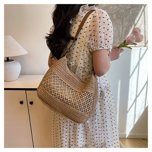 Detail of hand-woven straw shoulder bag with mesh patchwork texture and slim straps