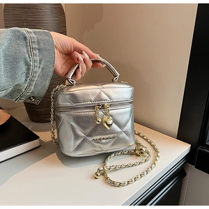 Détail du sac cylindrique argenté matelassé avec fermeture éclair cœur et bandoulière