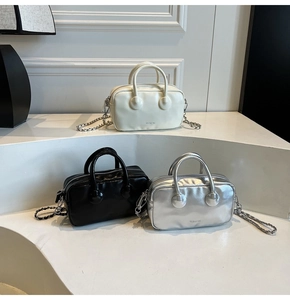 Detailed view of Boston bowling bags in cream, black, and silver with chain straps