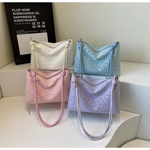 Détail de quatre grands sacs cabas en cuir aux tons pastel avec motifs en relief