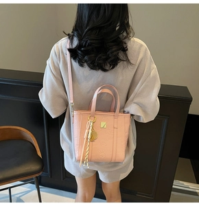 Close-up of pink embossed bucket bag with cute animal patterns and tassel charm detail