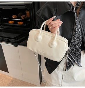 Detail of creamy white glossy Boston bag featuring silver chain and GLEAR'K lettering