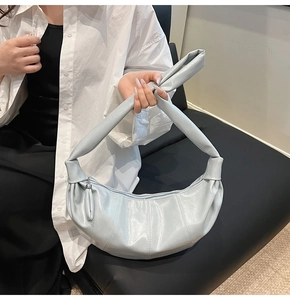 Detail of light blue crescent bag with pleated leather texture and metal zipper