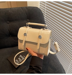Détail d'un sac à main rectangulaire crème avec clous argentés et bandoulière amovible
