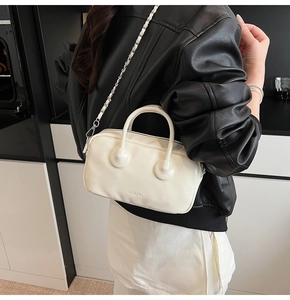Detail of cream bowling bag with silver chain strap and clearok logo on smooth texture