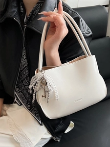 Minimalistische weiße Eimertasche aus Leder mit CLEARUK Logo und dekorativem Perlenanhänger