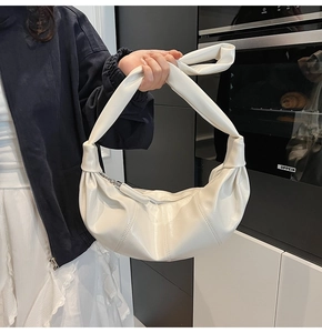 Detail view of cream dumpling bag showing pleated texture and knotted shoulder strap