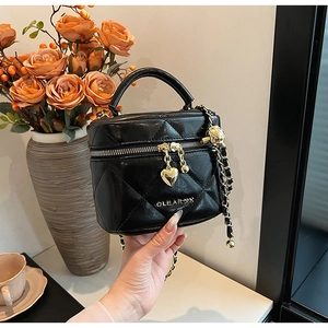 Détail du sac cylindrique matelassé noir avec zip cœur doré et bandoulière en chaîne