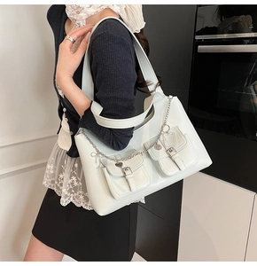 Close-up of white glossy tote bag featuring metal heart chains and utility pockets