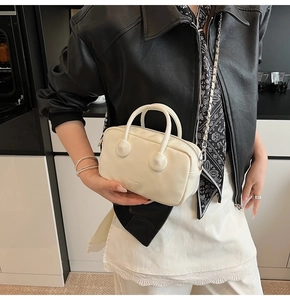 Detailed shot of cream mini bowling bag with silver chain strap and subtle logo embossing