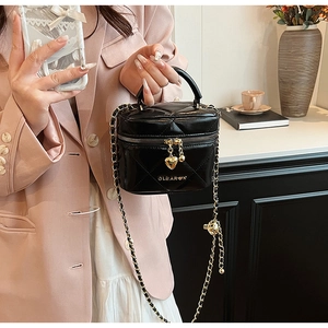 Détail du sac cylindrique matelassé noir avec zip cœur doré et bandoulière chaîne