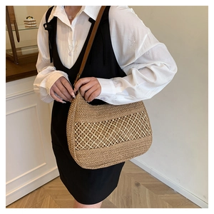 Detail of hollow woven straw shoulder bag with leather strap shown on shoulder