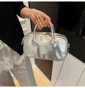 Detail of silver metallic Boston bag featuring top handle and elegant chain shoulder strap