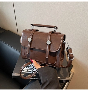Détail du sac bandoulière marron vintage avec rivets en métal et texture cuir lisse