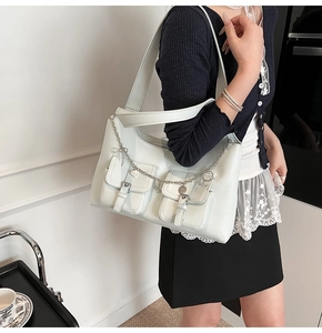 Detail of light blue faux leather tote bag featuring two front pockets and silver heart charms