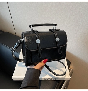 Détail du sac à main noir en cuir PU brillant avec boucles argentées et poignée