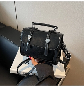 Détail du sac à main vintage noir brillant avec boucle argentée et poignée ronde