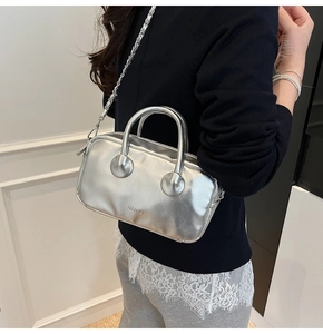 Detail of silver metallic purse with mirror finish, round handle and chain strap