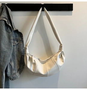 Detail of white pleated dumpling bag with knotted strap and soft textured faux leather