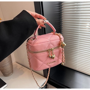 Détail d'un sac à main matelassé rose avec chaîne dorée et breloque en cœur