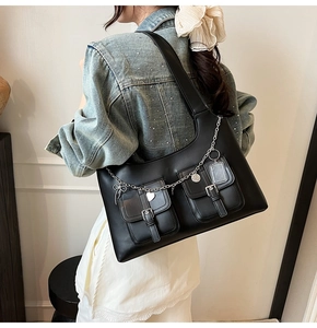Detail of black multi-pocket tote bag with silver heart and bow metal chains