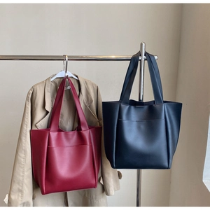 Detail view of large burgundy and black tote bags with front pockets on hangers