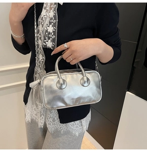 Silver metallic bowling bag styled as crossbody with chain strap and brand logo