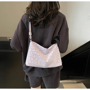 Détail du sac cabas lavande avec motifs géométriques sur une tenue texturée sombre