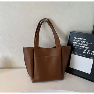 Close-up of a minimalist dark brown leather tote bag with a spacious front pocket