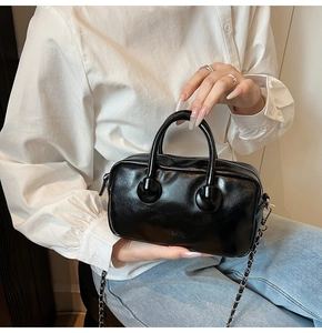 Close-up of black patent leather bowling bag with silver chain and glossy finish