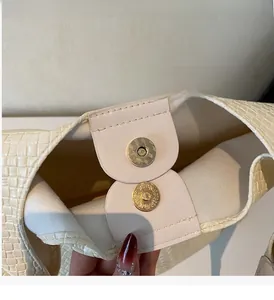 Detail of golden magnetic closure on cream woven texture tote bag with suede lining