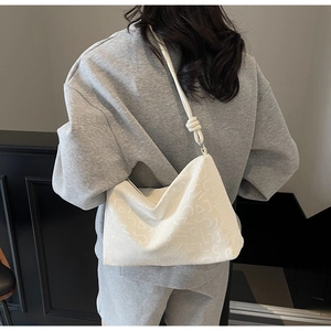 Détail du sac à bandoulière blanc en PU avec gaufrage géométrique et bandoulière nouée