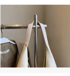 Detail of cream woven tote bag showing broad smooth handles and intricate textured pattern
