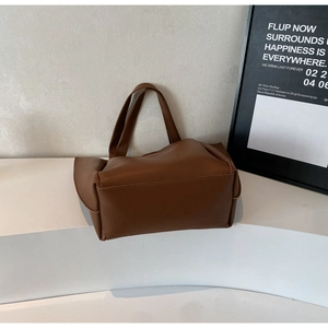 Detail shot of brown leather tote bag on minimalist white display with a modern background