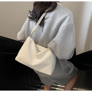 Détail du sac bandoulière en cuir blanc avec motifs géométriques et détails de nœuds