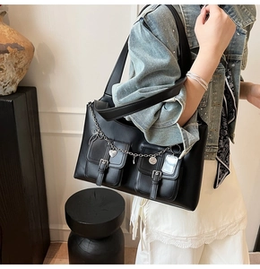 Detail of black faux leather tote bag featuring functional pockets and silver chain charms
