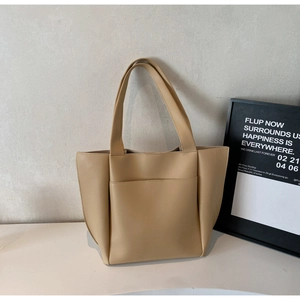 Detail of khaki tote bag featuring smooth leather texture and functional front pocket